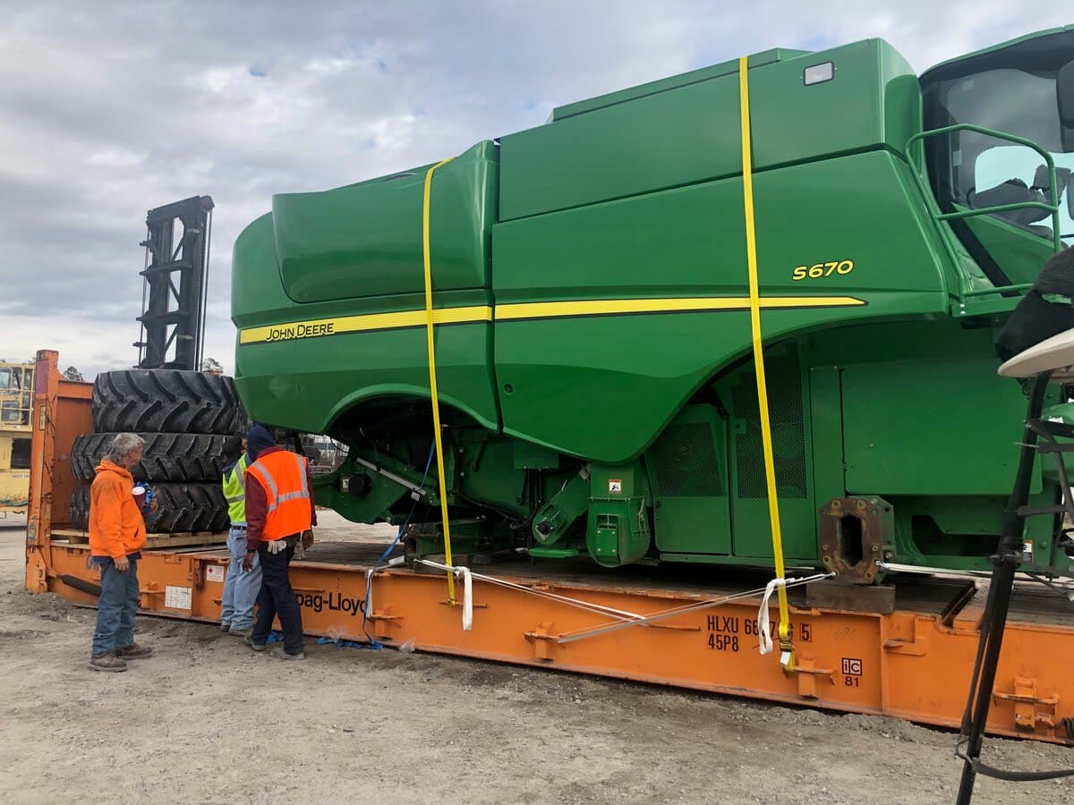 John Deere S670 combine being secured on a Hapag-Lloyd flat rack by crew in hi-vis vests